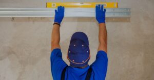 Man checking garage door track with level