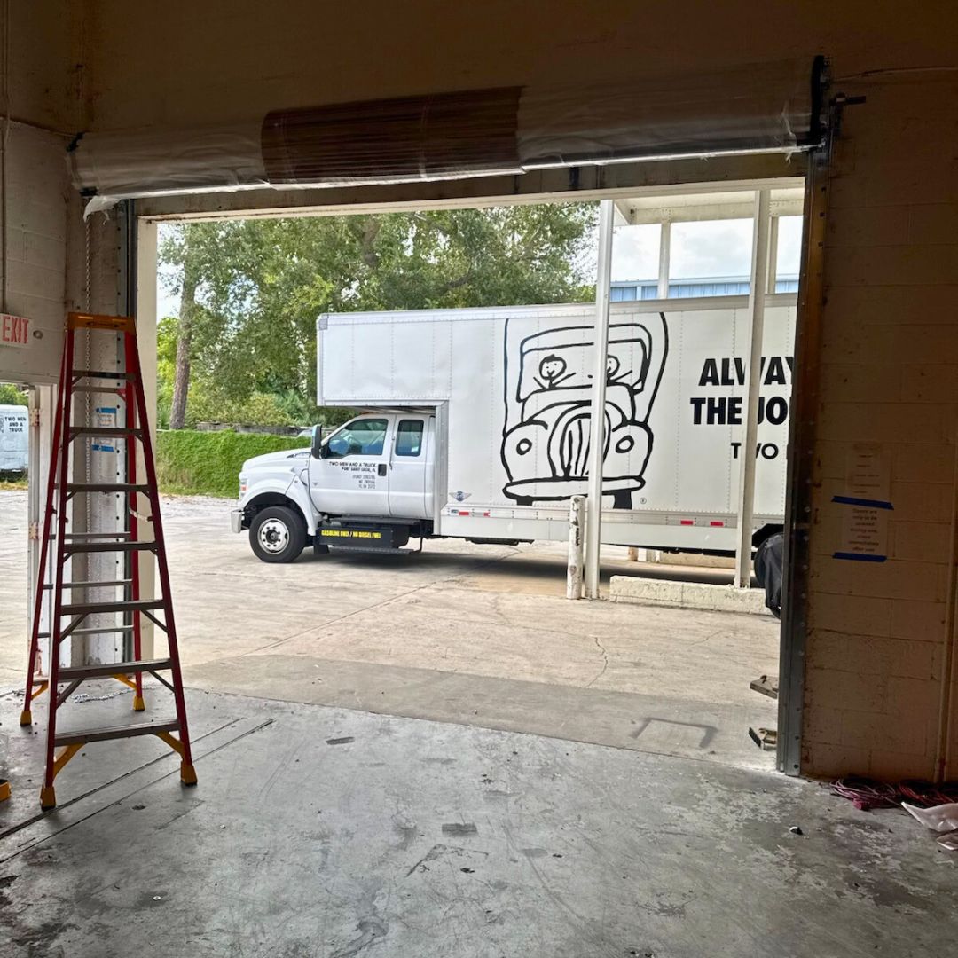 an open garage door with a moving truck parked in front